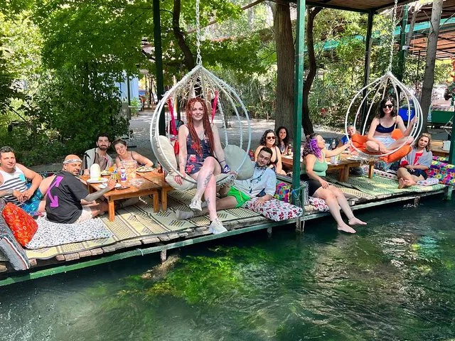 Group of people relaxing on floating platforms with swing chairs in a river