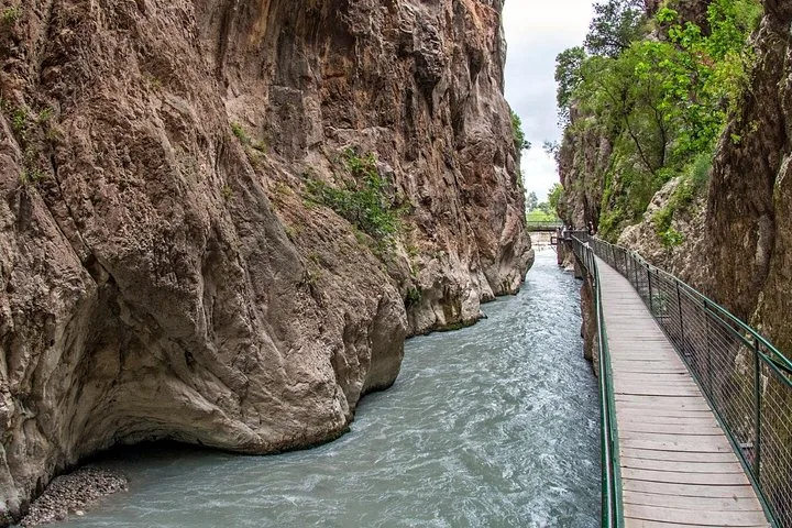 Walkway clinging to the rocky walls of a steep gorge above flowing water