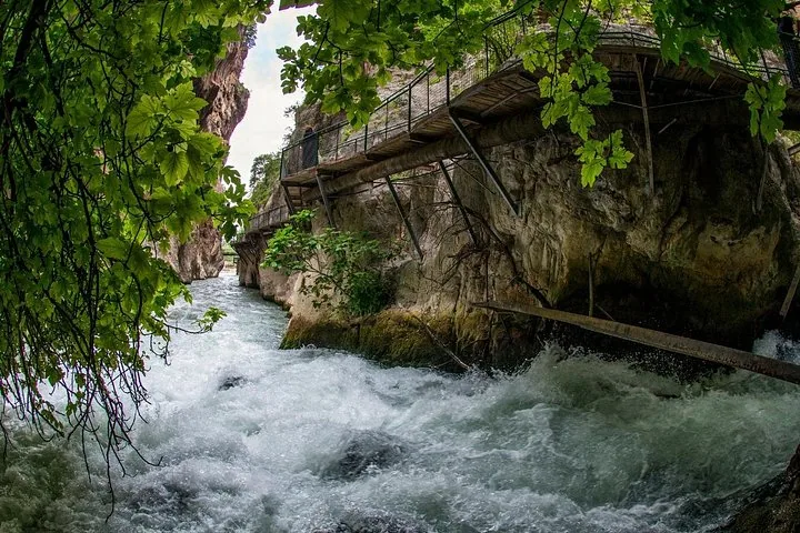 Turbulent white water flowing under a wooden walkway in a deep gorge